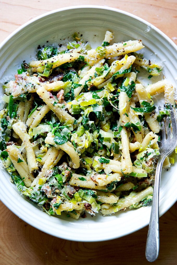 A plate of pasta carbonara with leeks and lemon on a plate.