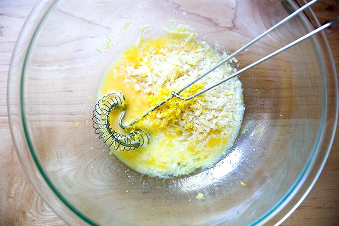 The sauce for the pasta carbonara in a bowl: eggs, lemon, parmesan, and pasta cooking liquid.