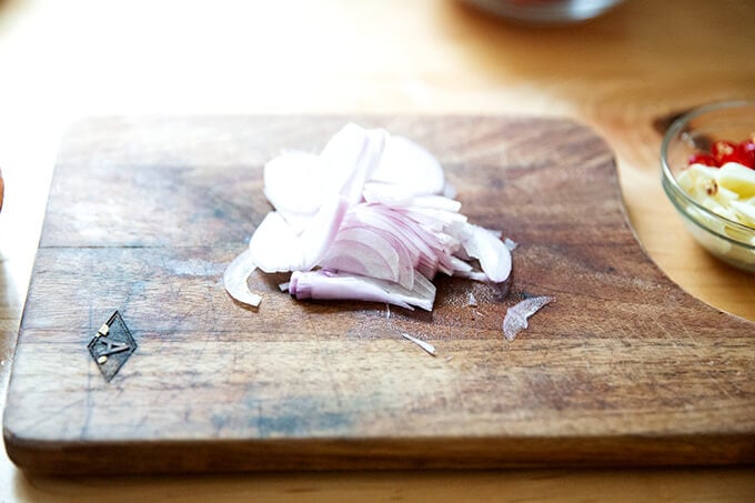 Sliced shallots on a cutting board.