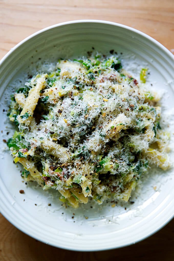 A plate of pasta carbonara showered with parmesan and fresh cracked pepper.