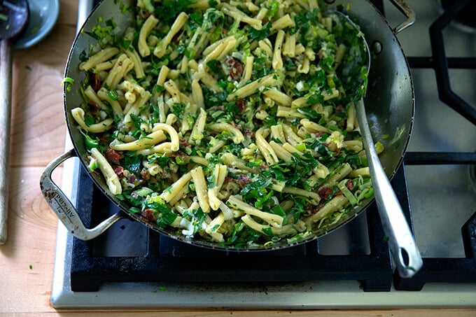 A skillet of pasta carbonara with leeks and lemon on the stovetop.