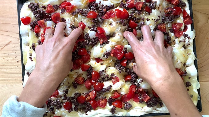 Dimpling an unbaked pissaladière.