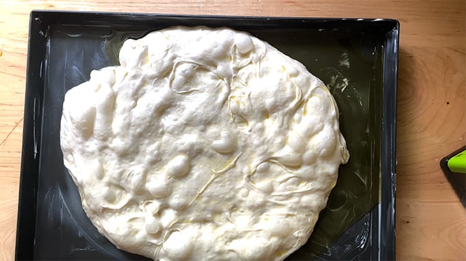 Sourdough pissaladière dough on a sheet pan.