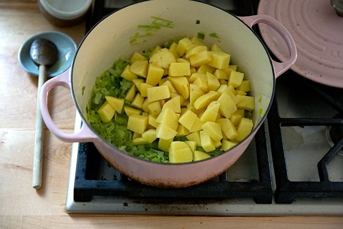 A large soup pot holding leeks and potatoes.