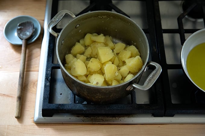 A pot of cooked potatoes on the stovetop.