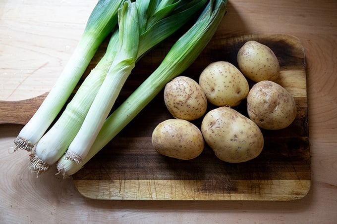 Leeks and potatoes on a board.