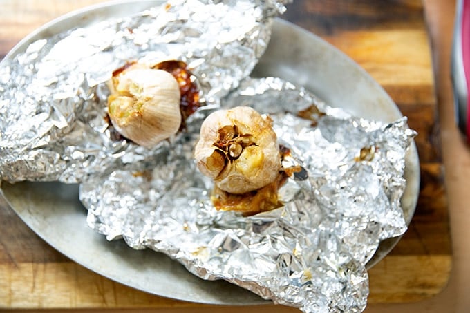 Roasted heads of garlic on sheets of foil.