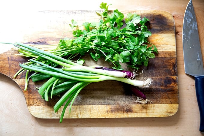 Scallions and cilantro on a cutting board.