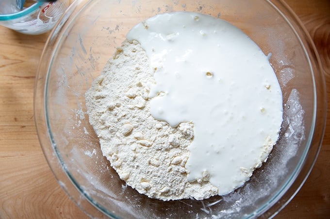 Adding buttermilk to a bowl of dry ingredients and butter.