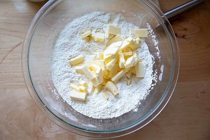 A large bowl of dry ingredients plus slices of butter.