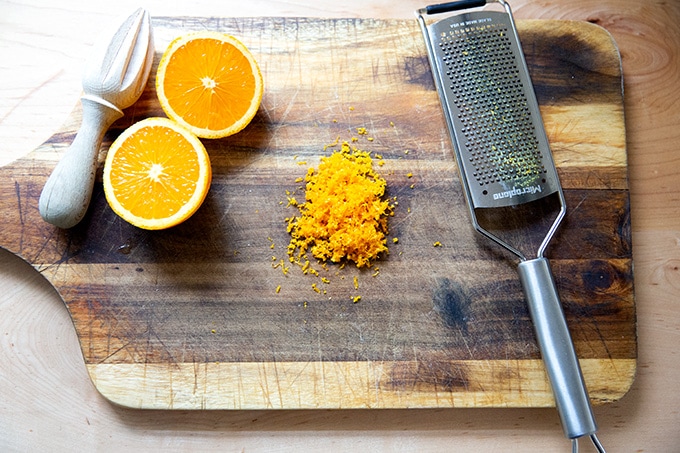 Orange zest on a cutting board aside a halved orange.