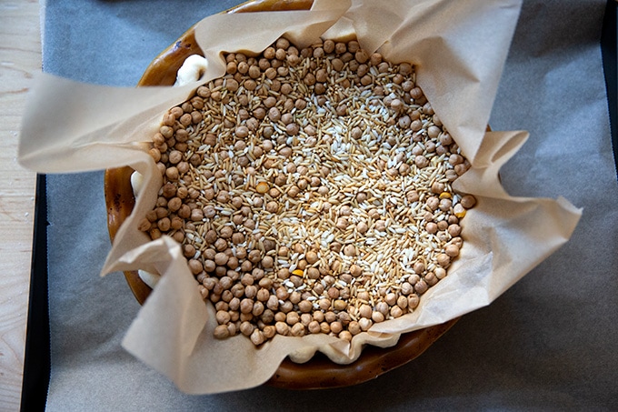 An unbaked pie shell filled with dried beans about to enter the oven to be parbaked. 