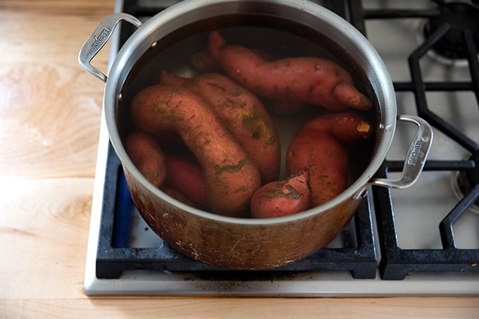 A large pot filled with sweet potatoes covered in water.