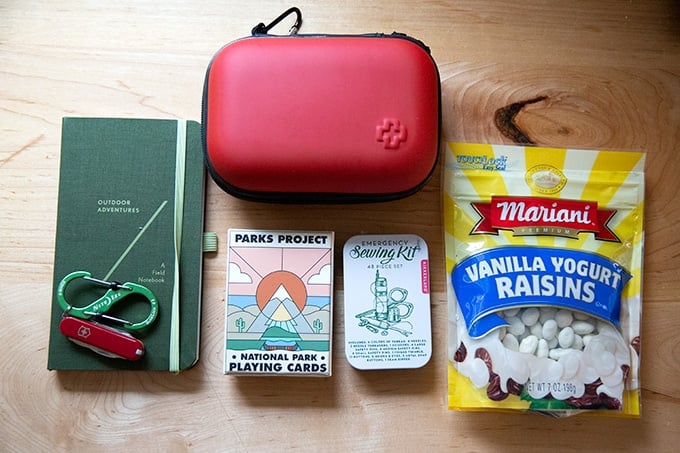 A notebook, first aid kit, journal, and deck of cards on a countertop.