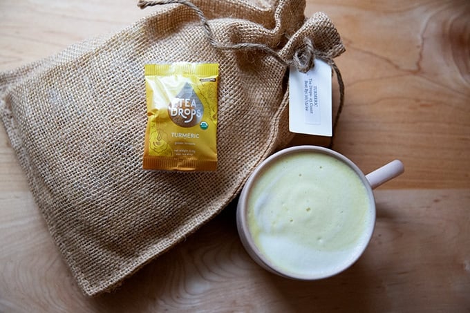 A turmeric latte next to a bag of turmeric tea.