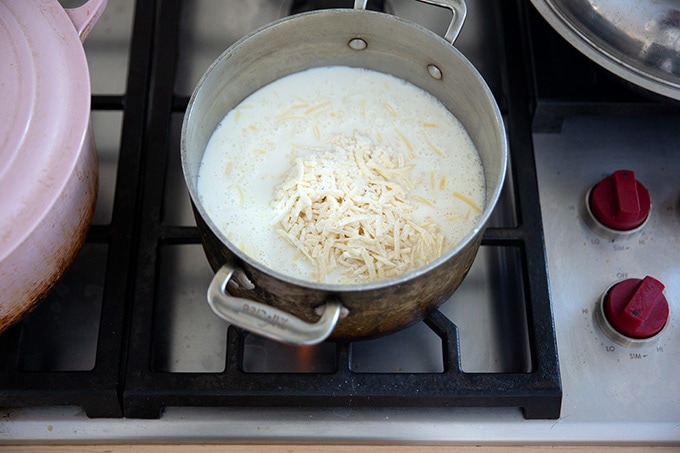 Cheese and milk in a pot on the stovetop.