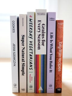 A stack of 6 cookbooks on a countertop.