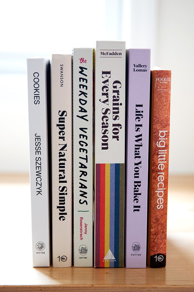 A stack of 6 cookbooks on a countertop. 