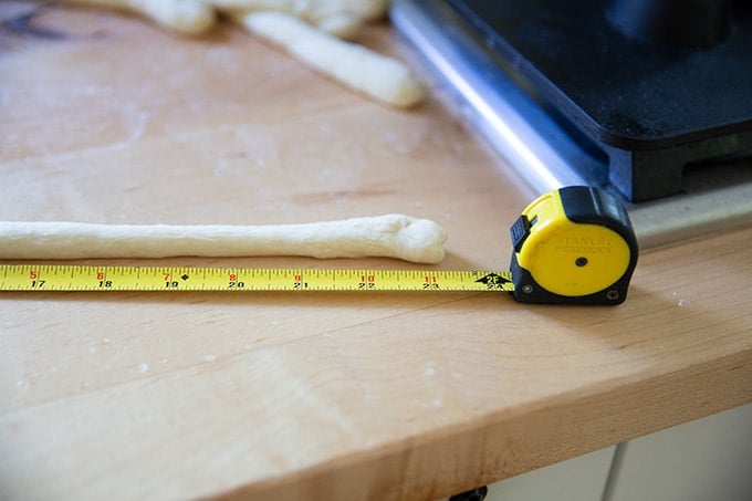 A tape measure next to a roll of pretzel dough.