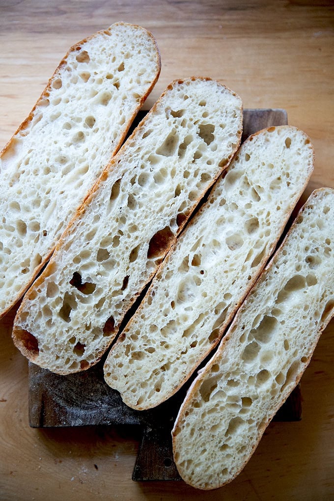 Two baguettes halved lengthwise to reveal the crumb on a cutting board.