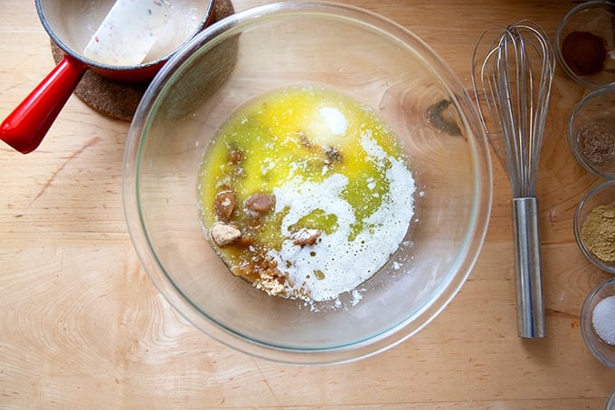 A large bowl filled with melted butter, sugar, and molasses aside a whisk.