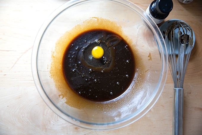 A bowl of gingersnap cookie batter with one egg added.