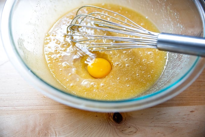 Adding the eggs one by one to a bowl of pound cake batter.