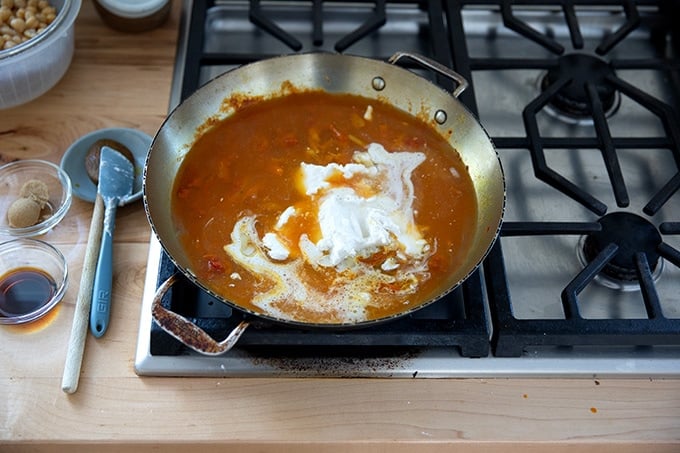 A skillet on the stovetop holding the makings of curried Thai chickpeas.