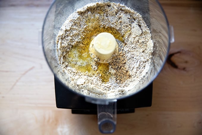 Wet ingredients added to dry ingredients for no-bake granola bars in a food processor.