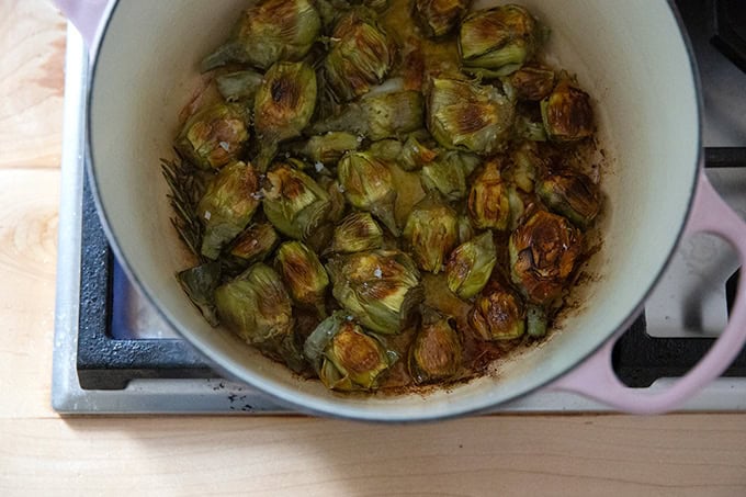 A large pot filled with baby artichokes crisped up and finished cooking on the stovetop. - 7