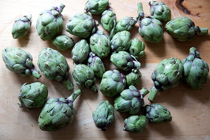 A countertop topped with a couple of pounds of baby artichokes. - 2