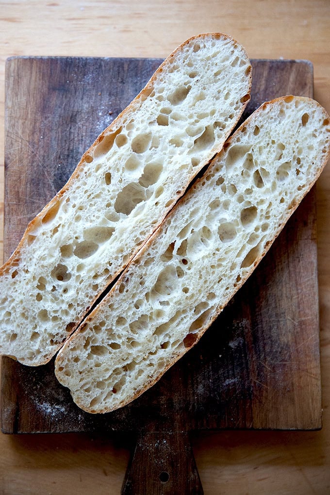 One halved baguette on a cutting board.