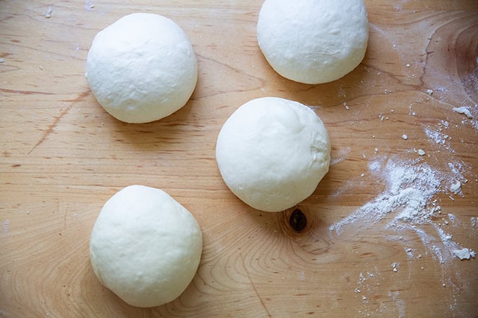 Four baguette dough balls all balled up.