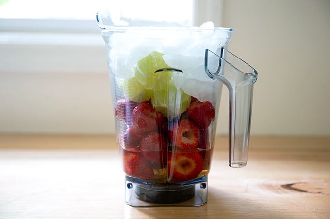 A blender filled with the ingredients to make strawberry paloma slushies.