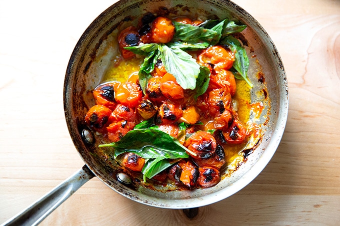 A skillet with blistered cherry tomatoes. 