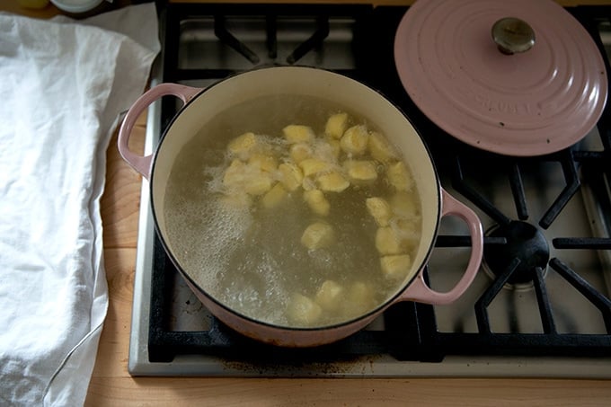 Ricotta gnocchi boiling in a large skillet.