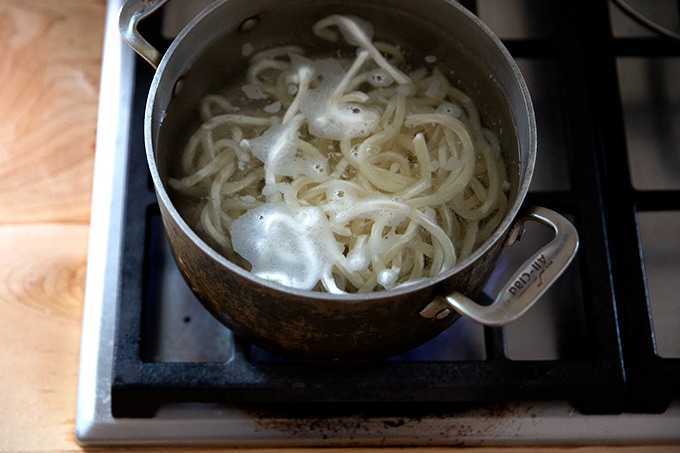 A pot of udon noodles boiling stovetop.