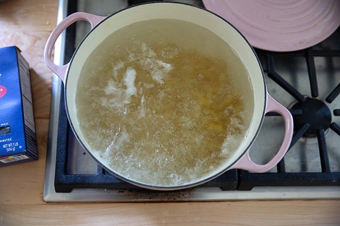 A large pot of water boiling with rotini inside.