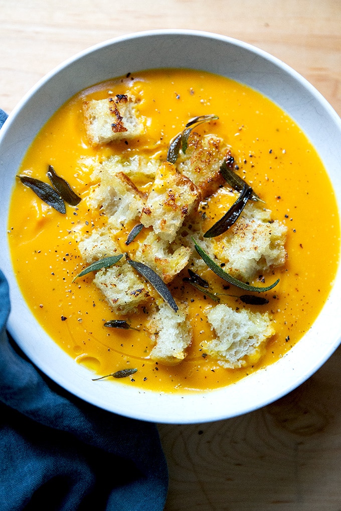 A bowl of roasted butternut squash soup topped with croutons and fried sage.