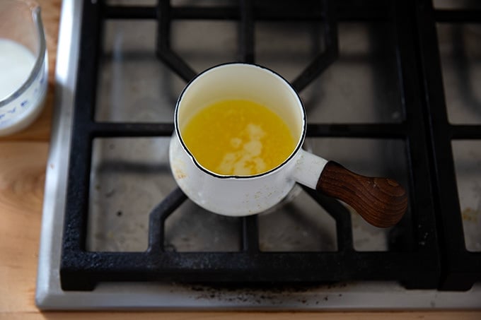 A small pot holding melted butter on the stovetop.