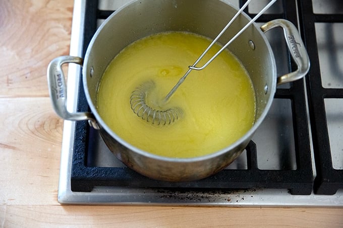 Melted butter and sugar whisked together in a pot on the stovetop.