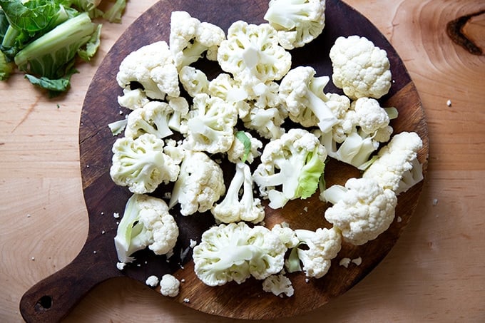 A cutting board topped with cauliflower florets.