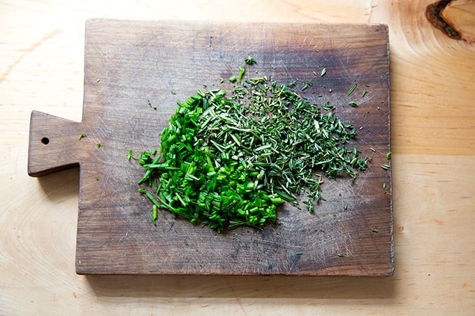 A board topped with chopped herbs.
