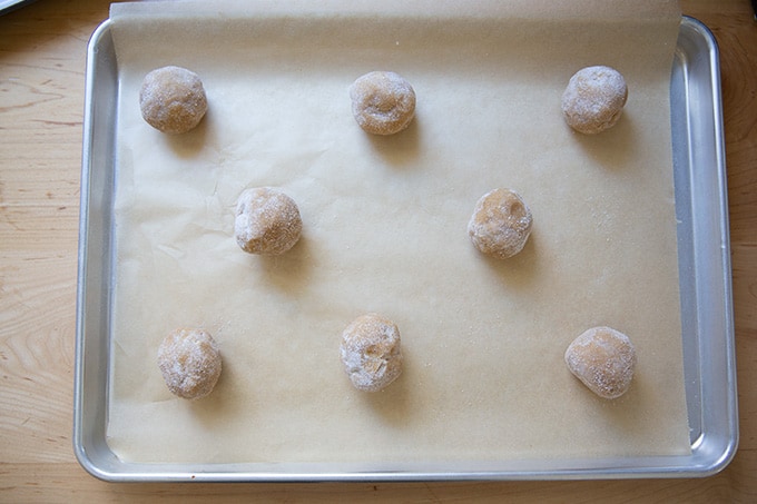 A sheet pan holding sugar-coated peanut butter cookie dough balls.