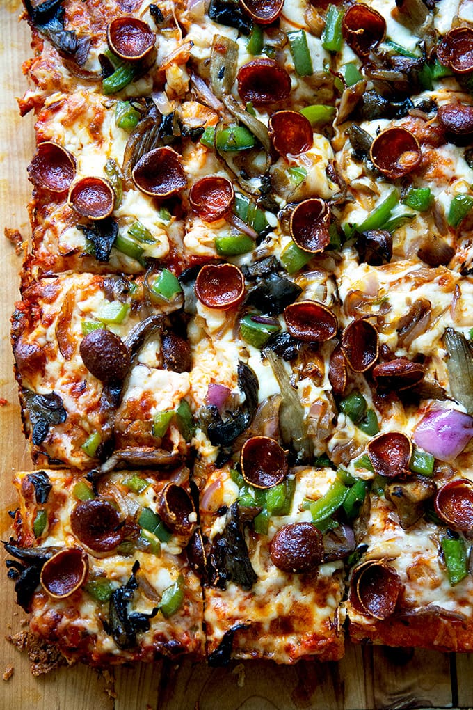 Just-baked Sicilian-style pizza cut into squares on a board.