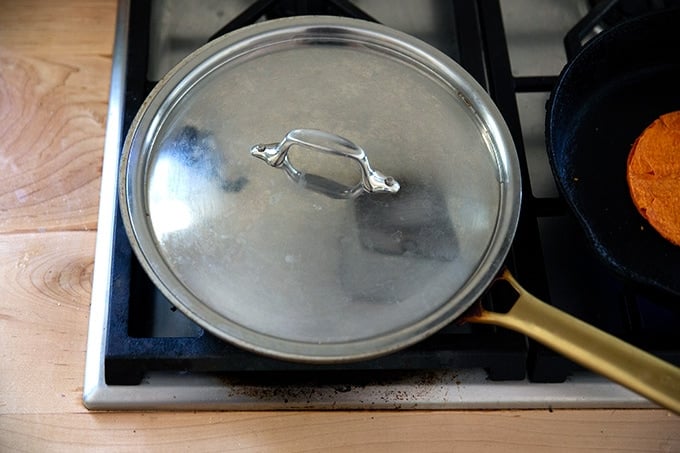 A skillet covered on the stovetop.