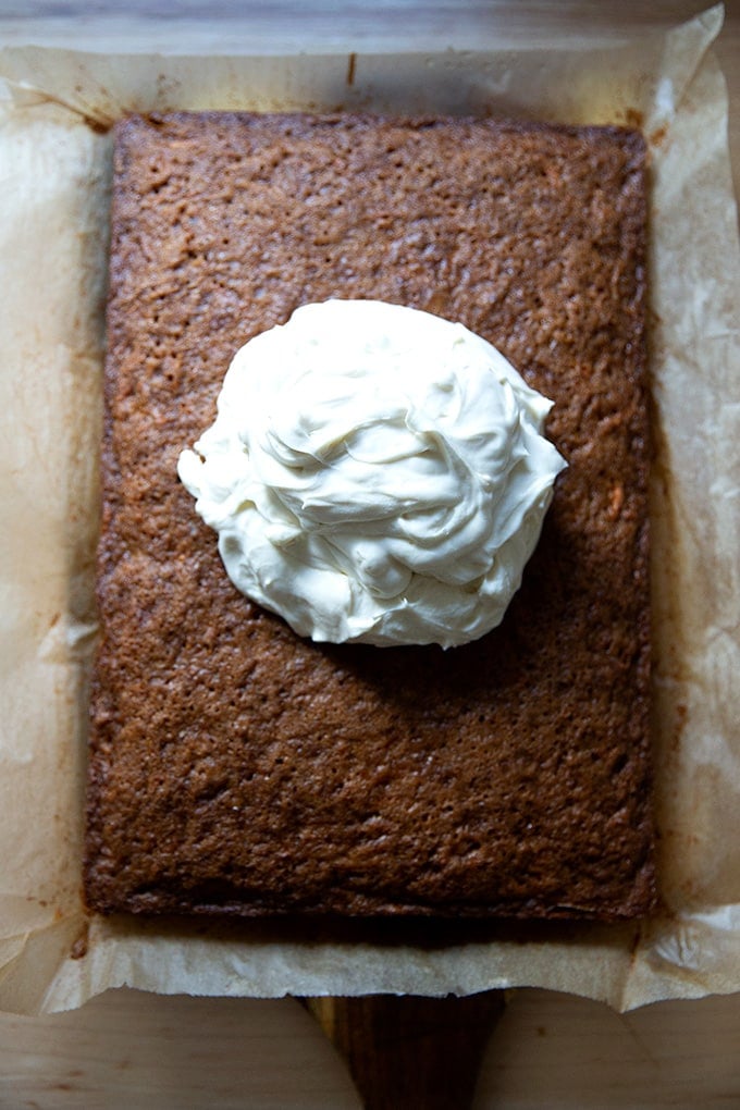 A big blog of cream cheese frosting in the center of a just-baked carrot cake.