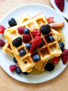 A plate of sourdough discard waffles topped with berries and syrup.