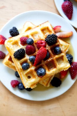 A plate of sourdough discard waffles topped with berries and syrup.