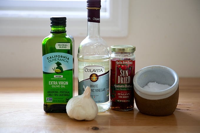 Ingredients to make the sun-dried tomato dressing for a bean salad on a countertop.